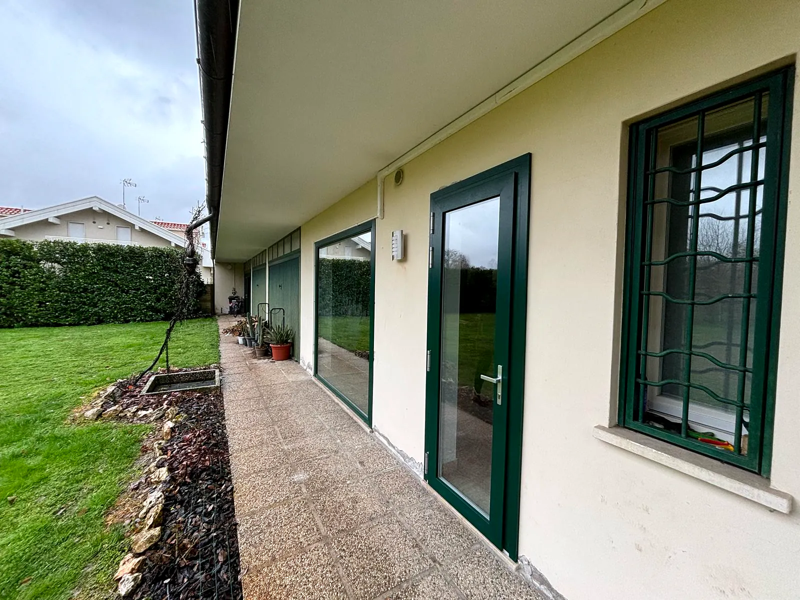 Serramenti verdi lungo il porticato di una casa con giardino