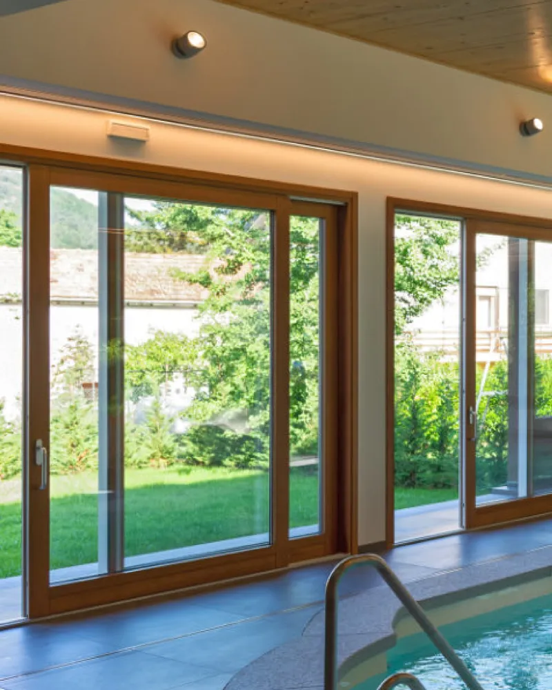 Alzante scorrevole in legno affacciato sul giardino, accanto a una piscina coperta