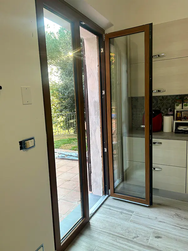 Porta-finestra effetto legno aperta sul giardino